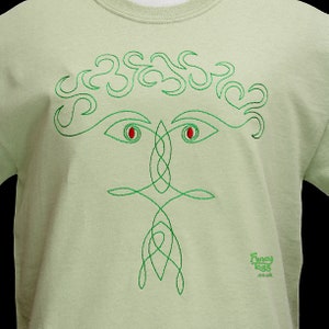 Pu&ograve; includere: Una maglietta verde chiaro con un disegno di nodo celtico ricamato in verde che rappresenta un viso con occhi rossi. Il disegno &egrave; centrato sulla maglietta. Il testo "Fancy Lugs .co.uk" &egrave; ricamato nell'angolo in basso a destra della maglietta.