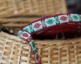May include: Red, green, and white patterned trim with a black center. The trim is rolled up and sitting in a wicker basket.