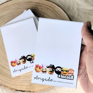 Pode incluir: Blocos de notas brancos com uma fileira de emojis na parte inferior. Os emojis incluem corações, chapéus de pirata e óculos de sol. A palavra "obrigado" está escrita em itálico abaixo dos emojis, com o texto "por est" e "#lucas8" também visíveis.