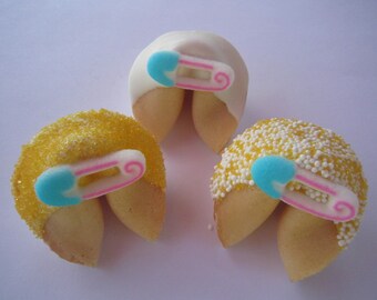May include: Three fortune cookies decorated with sprinkles and a blue and pink safety pin. The cookies are a light brown color and are open to reveal the inside.