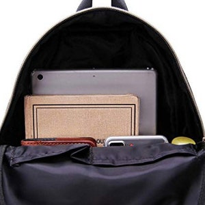 May include: A black backpack with a zippered top opening. The backpack is open and has a laptop, a notebook, a wallet, and a phone inside.