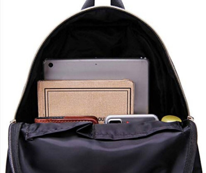 May include: A black backpack with a zippered top opening. The backpack is open and has a laptop, a notebook, a wallet, and a phone inside.