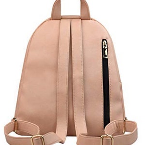 May include: A blush pink faux leather backpack with adjustable straps and a zippered pocket on the side. The backpack has gold hardware.