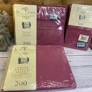 Pode incluir: Três pacotes de lençóis de cama de tamanho duplo na cor bordô. Os pacotes são etiquetados com "Select Edition" e "The Very Best Always". Um pacote é para um lençol plano, um para um lençol com elástico e um para uma fronha padrão. Todos os pacotes são etiquetados com "200 fios" e "Sem rugas".