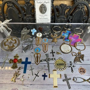 May include: A collection of religious-themed items, including crosses, angel figurines, keychains, and bookmarks. The items are in various colors, materials, and sizes, with some featuring the word "Blessed" and the text "Faithful Angels".