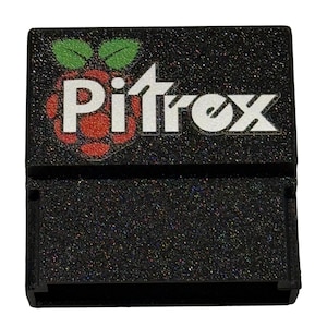 May include: Black rectangular electronic device with the word "Pitrox" in white and a red raspberry logo. The device has a glittery texture and a slot on the bottom. The raspberry logo has green leaves.