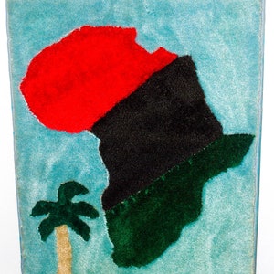 Peut inclure: Une tenture murale en feutre bleu avec un contour en feutre vert, noir et rouge du continent africain. Un petit palmier se trouve à gauche de l'image.