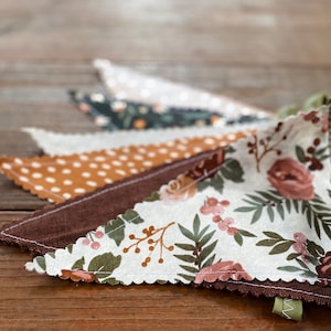 May include: A garland of fabric pennants with different patterns. The pennants are brown, white, and tan with floral and polka dot designs.