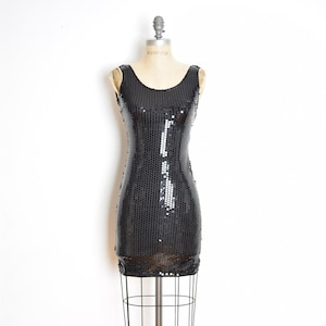 May include: A black sequined sleeveless dress on a dress form. The dress is fitted and has a scoop neckline.