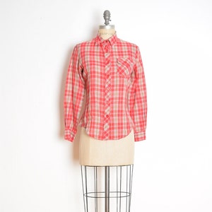 May include: A red and white plaid long-sleeved shirt with a button-down collar and a single chest pocket.