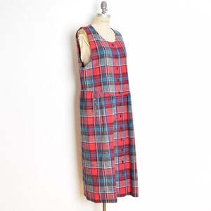 May include: A red, blue, and gray plaid sleeveless dress with a button-up front. The dress is on a mannequin and has a slightly flared skirt.