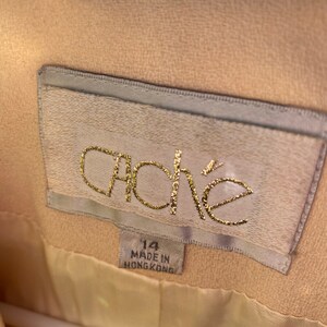 May include: A beige jacket with a white label that says "ache" in gold lettering. The label also says "14" and "Made in Hong Kong".