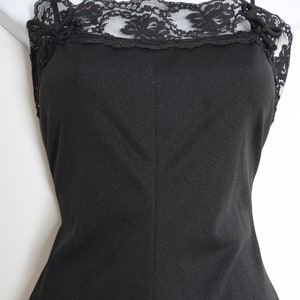Puede incluir: Un vestido negro sin mangas de sat&eacute;n con un borde de encaje alrededor del escote.