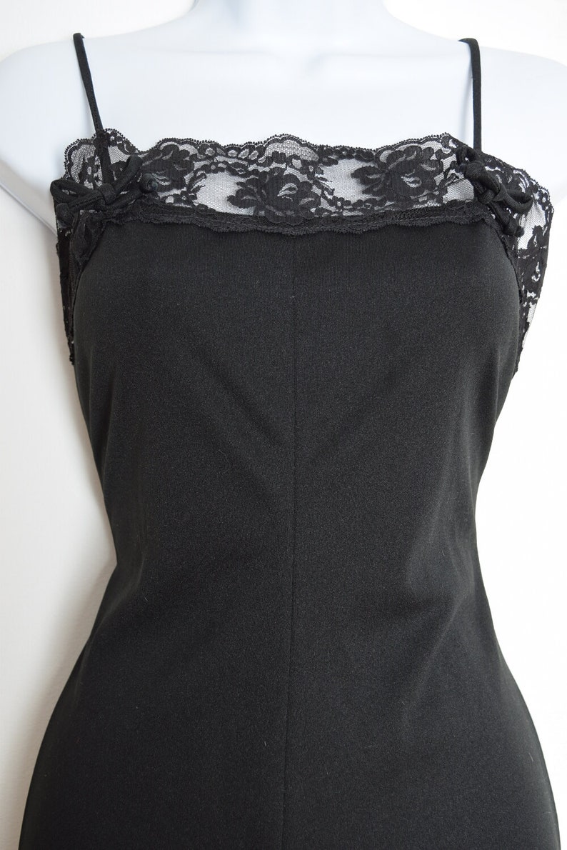 Puede incluir: Un vestido negro sin mangas de sat&eacute;n con un borde de encaje alrededor del escote.