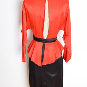 May include: A red and black dress with a fitted skirt and a peplum top. The dress has a keyhole back and a black belt.