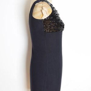 May include: A black sleeveless dress with a sequined detail on the shoulder.