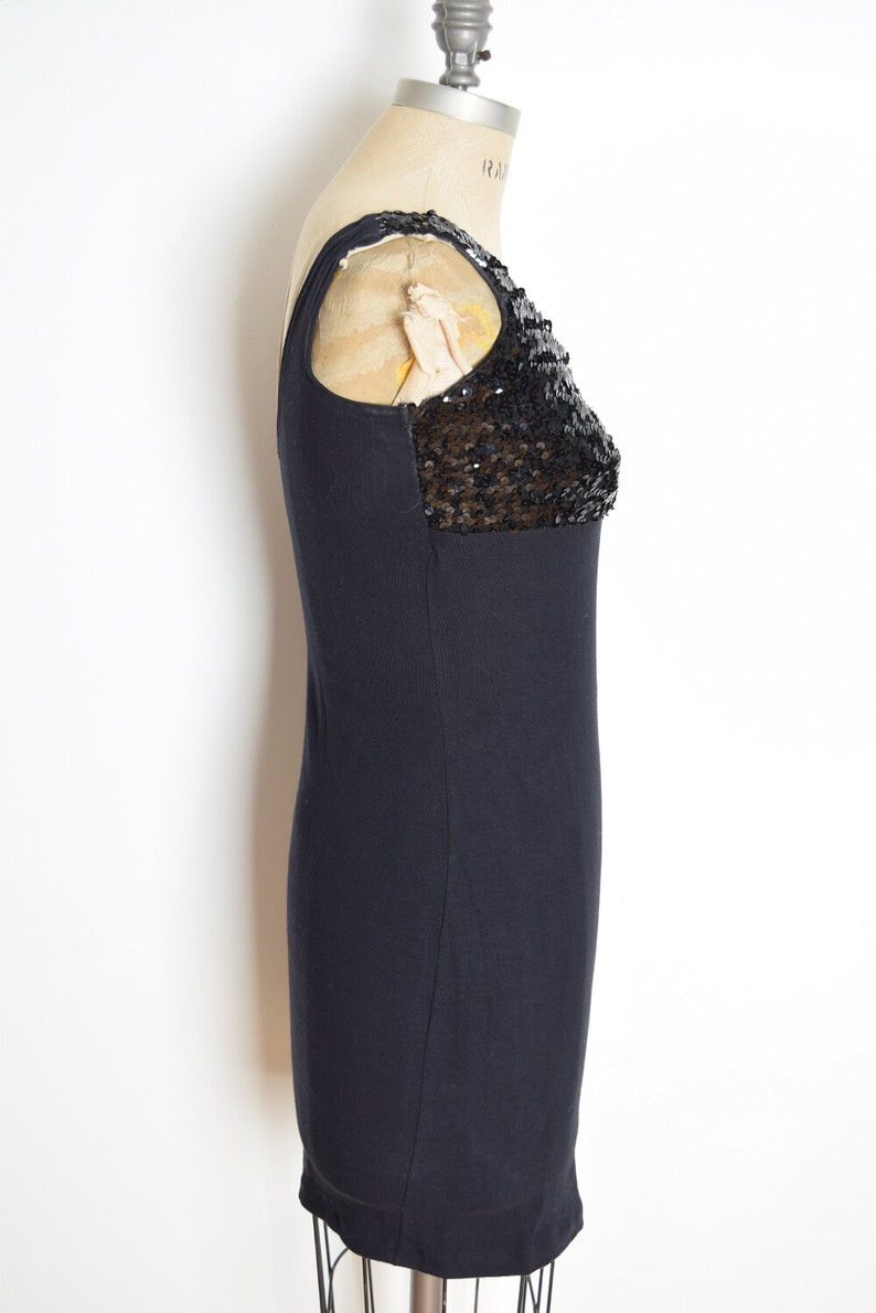 May include: A black sleeveless dress with a sequined detail on the shoulder.