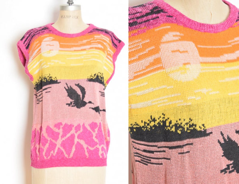 May include: A pink, yellow, and orange sleeveless sweater with a sunset and bird design. The sweater is knitted and has a crew neck.