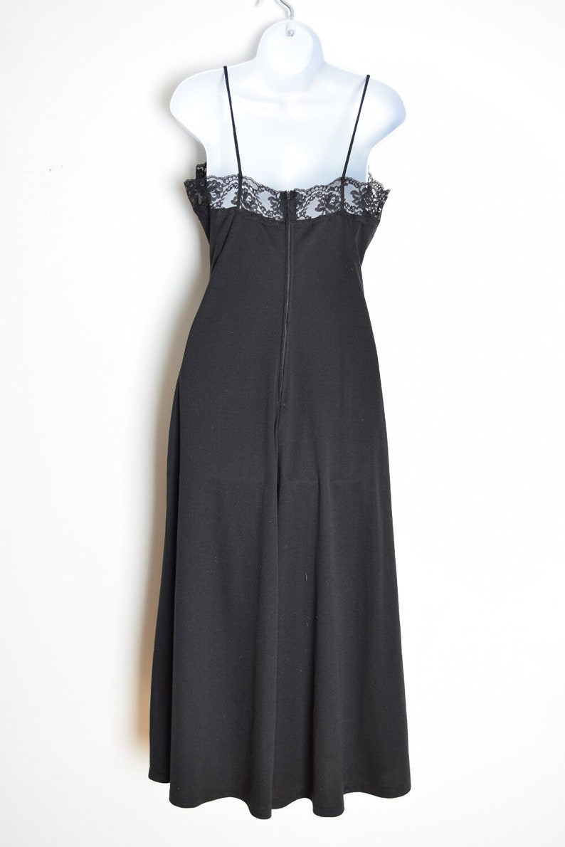 Puede incluir: Un vestido negro maxi con un borde de encaje en el escote. El vestido tiene una cremallera en la espalda.