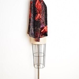 May include: A long-sleeved top with a patchwork design. The top features a mix of patterns and colors, including red, black, and purple. The garment is displayed on a mannequin.