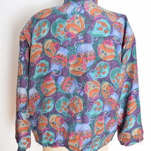 May include: A blue, green, orange, and purple patterned jacket with a high collar and zipper closure.