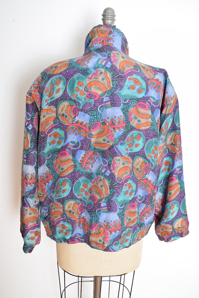 May include: A blue, green, orange, and purple patterned jacket with a high collar and zipper closure.