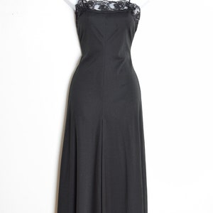 Puede incluir: Un vestido negro maxi con un escote de encaje. El vestido tiene tirantes finos y una falda fluida.