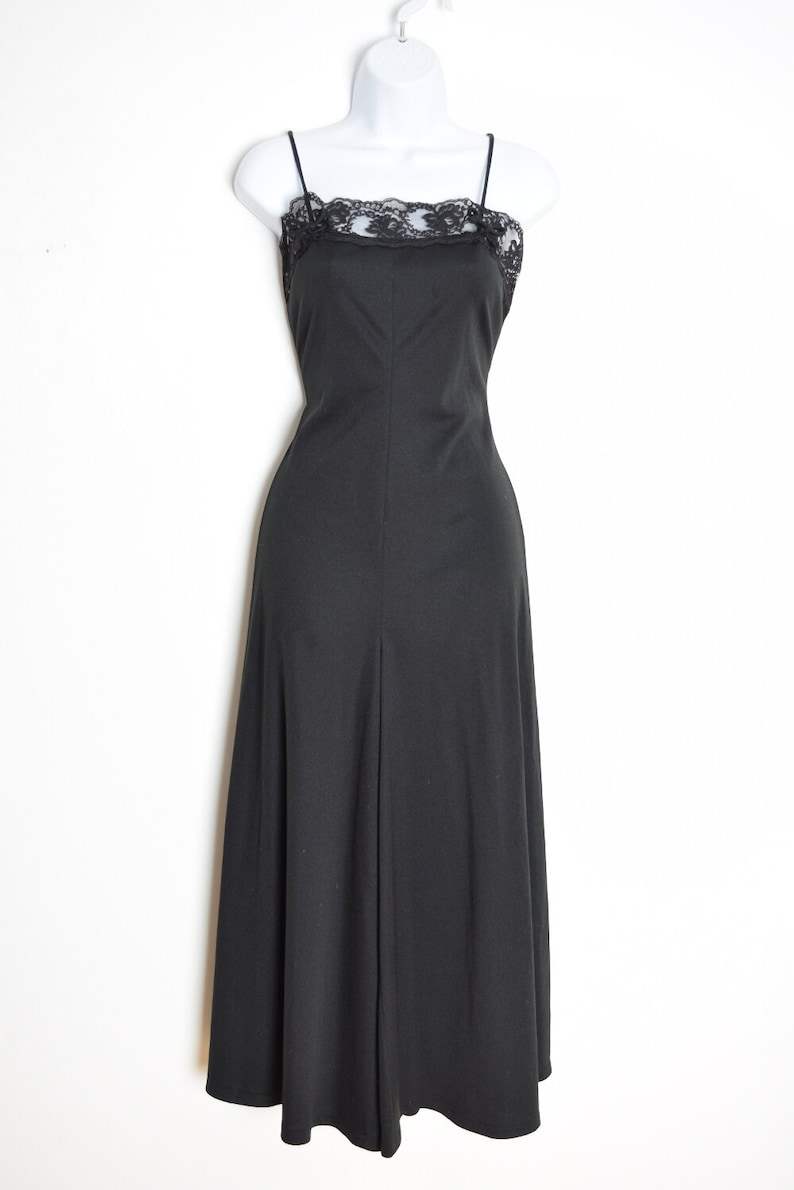 Puede incluir: Un vestido negro maxi con un escote de encaje. El vestido tiene tirantes finos y una falda fluida.