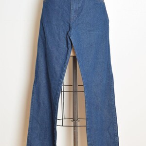 May include: Blue denim jeans with a high waist and flared leg. The jeans have classic five-pocket styling and a button and zipper closure. The garment is displayed on a mannequin.