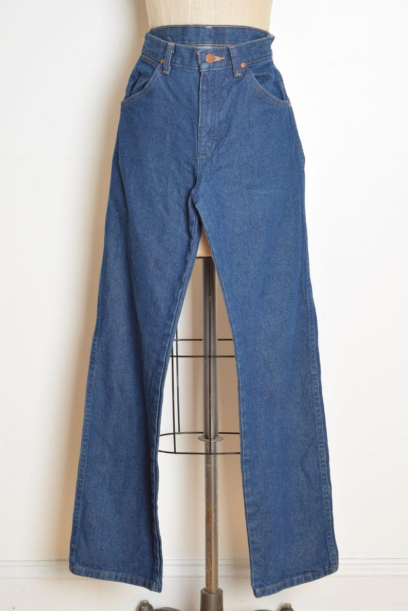 May include: Blue denim jeans with a high waist and flared leg. The jeans have classic five-pocket styling and a button and zipper closure. The garment is displayed on a mannequin.