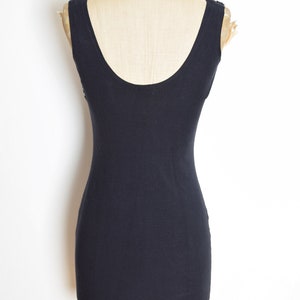 May include: A black sleeveless dress with a scoop neck. The dress is fitted and has a simple design.