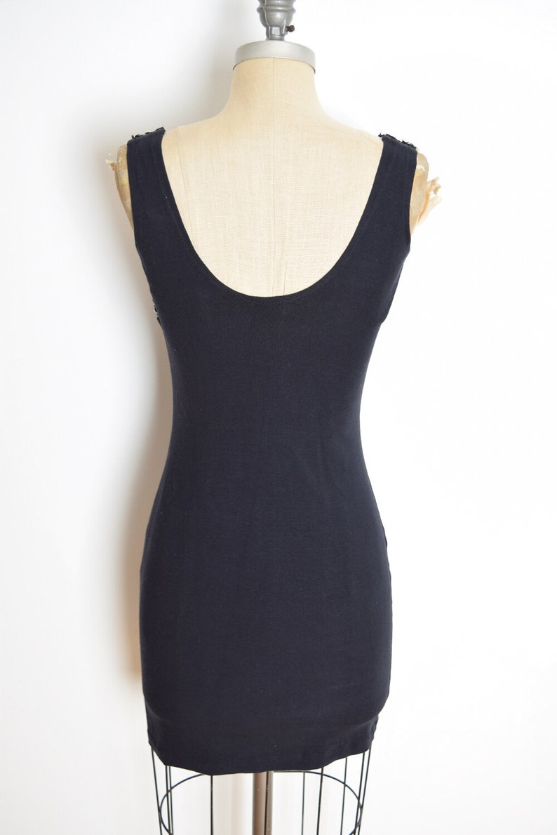 May include: A black sleeveless dress with a scoop neck. The dress is fitted and has a simple design.