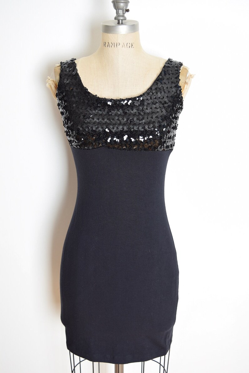 May include: A black sleeveless dress with a sequined bodice and a fitted skirt.