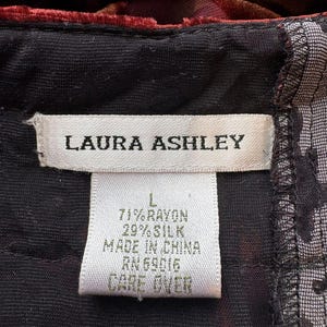 May include: Close-up of a clothing tag from Laura Ashley. The tag is white with black text, including the brand name, size, and fabric composition: 71% rayon, 29% silk. The tag also indicates the item was made in China.