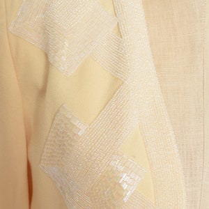 May include: A pale yellow blazer with a decorative design of white beads sewn in a geometric pattern.