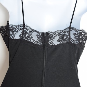Puede incluir: Vestido negro sin mangas con un borde de encaje en el escote y una cremallera en la espalda.