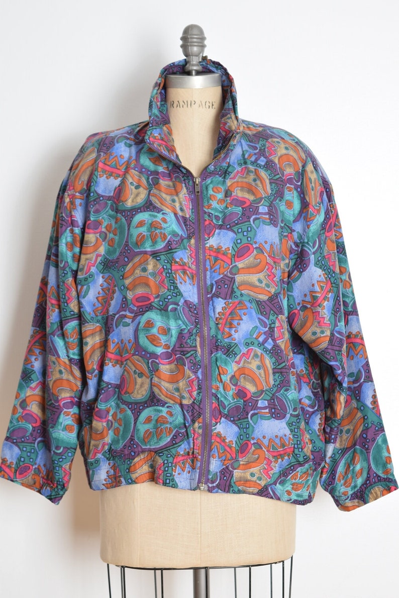 May include: A purple, blue, green, orange, and brown patterned jacket with a zipper closure. The jacket is on a mannequin.