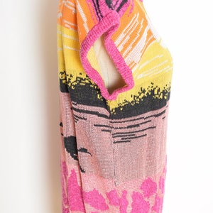 May include: A pink, orange, yellow, black and white striped knit sweater with a short sleeve design. The sweater has a floral pattern at the bottom.