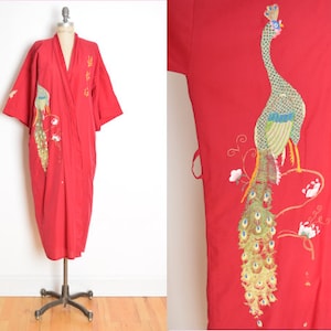 May include: A red robe with a peacock embroidered on the front. The peacock is green, blue, and gold. The robe has a wrap style and is made of a soft, silky fabric.