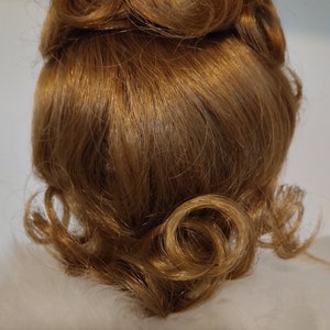 May include: A close-up of a brown wig styled in a vintage updo with curls. The wig is made of synthetic hair and has a natural-looking finish.