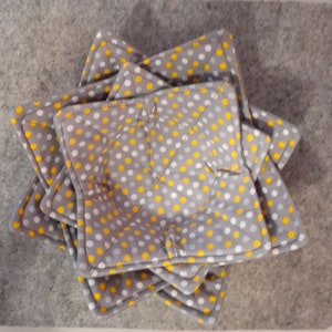 May include: Set of four grey and yellow polka dot pot holders. The pot holders are shaped like stars and are made of fabric.