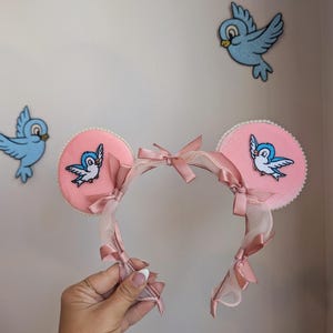 Orejas de Mickey inspiradas en Cindy con diseño de pájaro azul y cabaña de perlas. Orejas de ratón de perlas para los parques