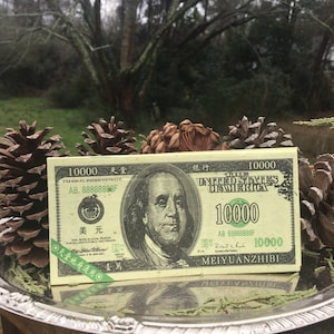 May include: A green and white novelty bill with a portrait of Benjamin Franklin and the text "10000" printed on it. The bill also has the text "United States of America" and "Federal Reserve Note" printed on it.