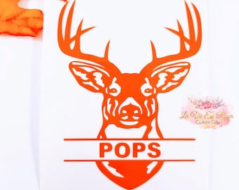 May include: A bright orange vinyl decal featuring a stylized deer head silhouette with large antlers. The design includes a horizontal split section across the neck area containing the text POPS in bold, uppercase, orange capital letters.