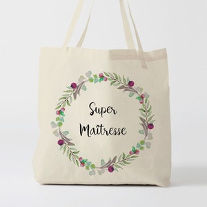 Könnte beinhalten: Eine weiße Canvas-Tragetasche mit einem floralen Kranzdesign und dem Text "Super Maitresse" in Schwarz.