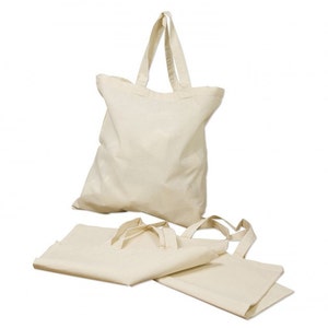 May include: Three natural-colored canvas tote bags. One bag has handles and is folded, while the other two are flat and unfolded.