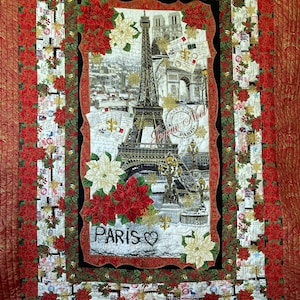 May include: A quilted wall hanging featuring a central image of the Eiffel Tower in Paris, France, surrounded by red and white poinsettias and the word "Paris". The border is a mix of red, white, and green floral patterns.