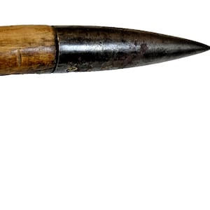 May include: A curved wooden tool with a metal tip. The wooden handle is light brown with visible grain, and the metal tip is dark and pointed. The two parts are joined by a dark metal band. The tool is isolated on a white background.