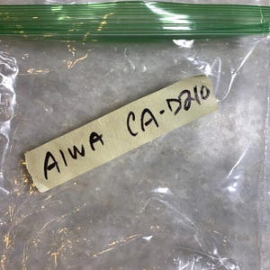 May include: A clear plastic bag with a yellow label that says "AIWA CA-D210".