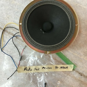 Puede incluir: Un altavoz negro con un borde dorado y una etiqueta que dice "Radio Shack MC-1000 40-1980A".